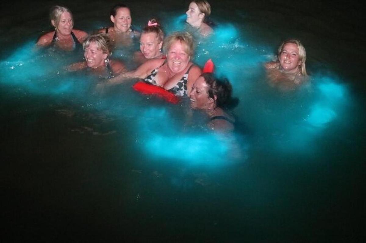 Un grupo de personas en el agua por la noche.