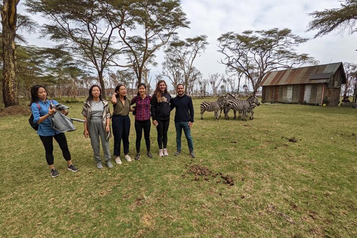 eine Gruppe von Menschen steht auf einem Feld mit Zebras
