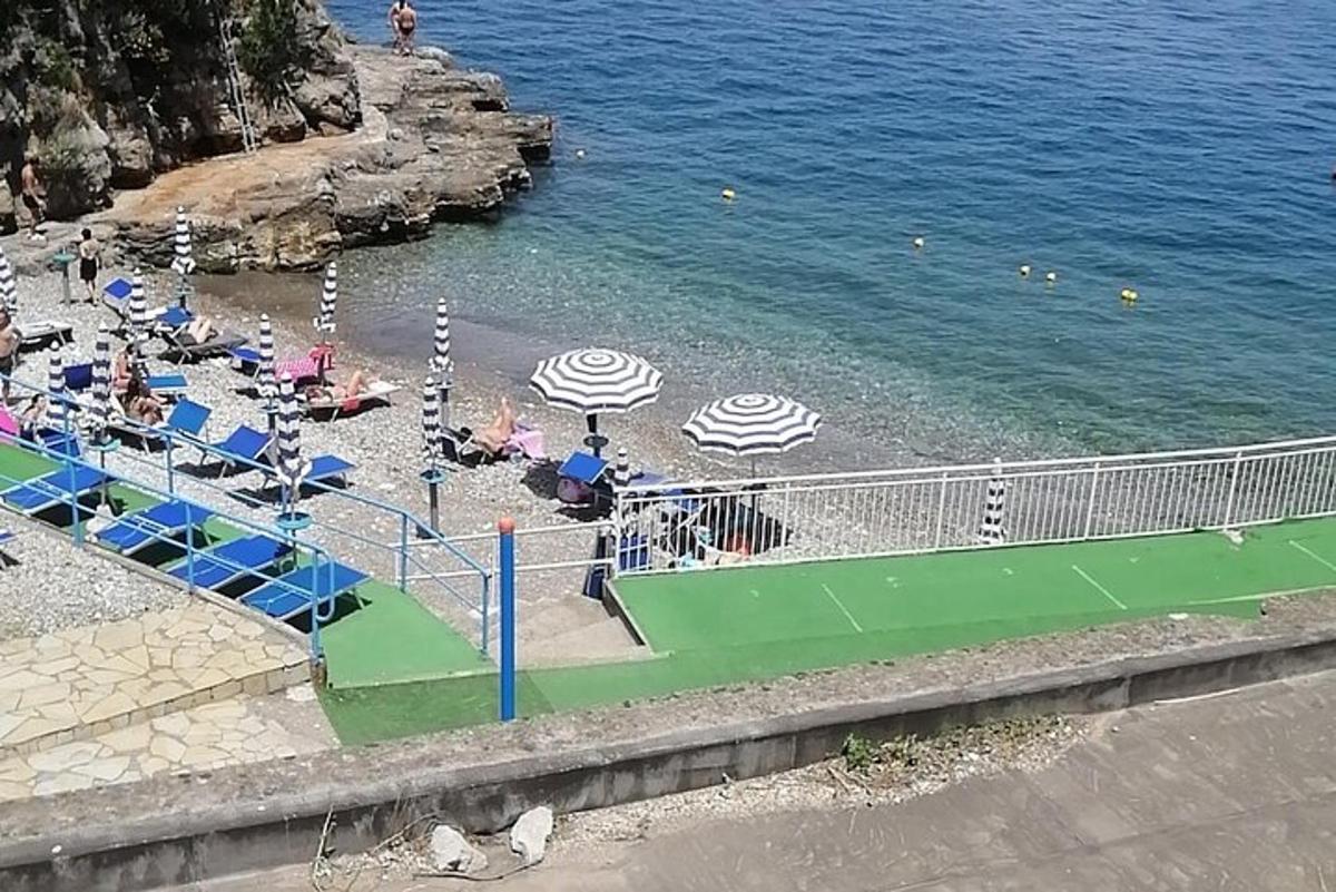 paplūdimys su gultais, skėčiais ir vandeniu