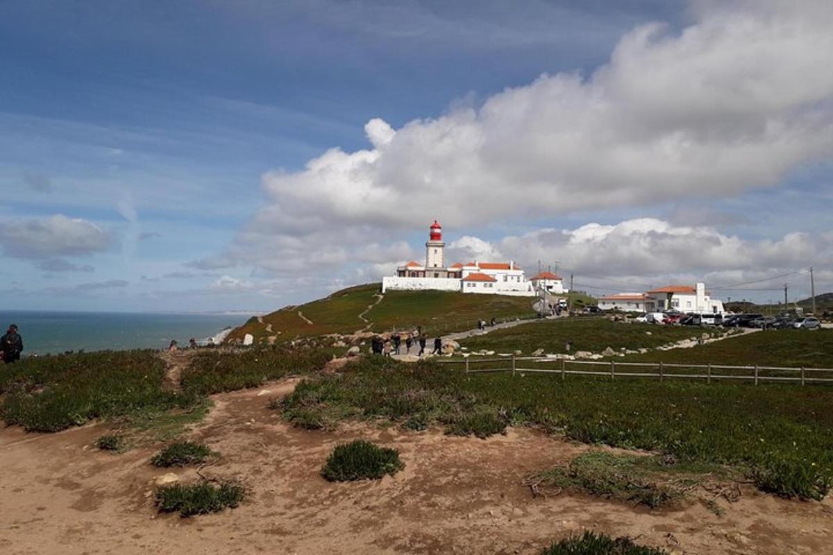 a lighthouse sitting on top of a hill next to the ocean