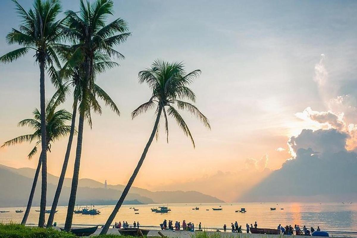 sekumpulan orang berdiri di pantai dengan pokok palma