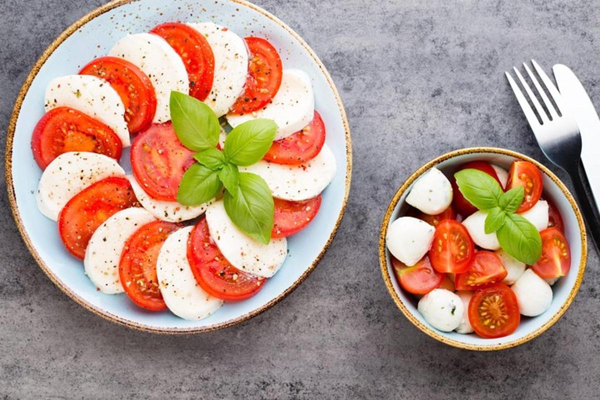 two plates of food with tomatoes and a bowl with a fork