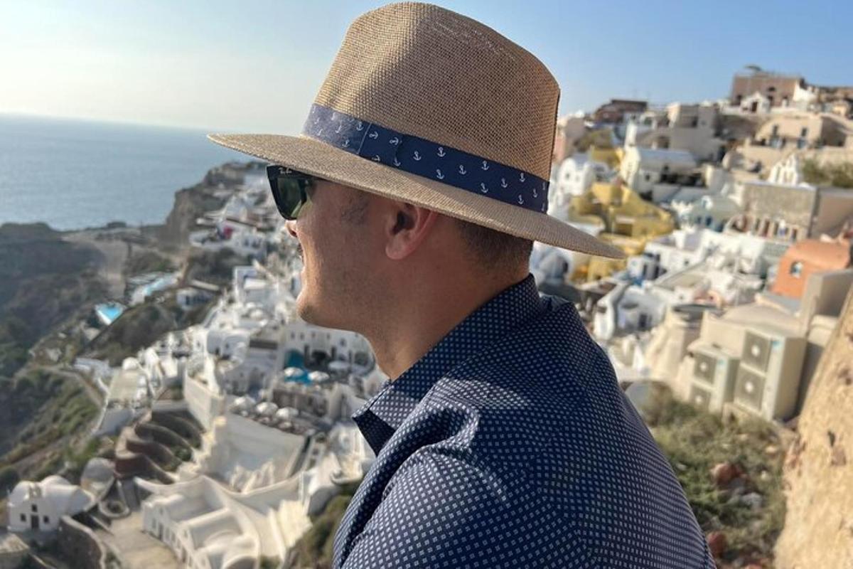 Un hombre con sombrero y gafas de sol mirando una ciudad.