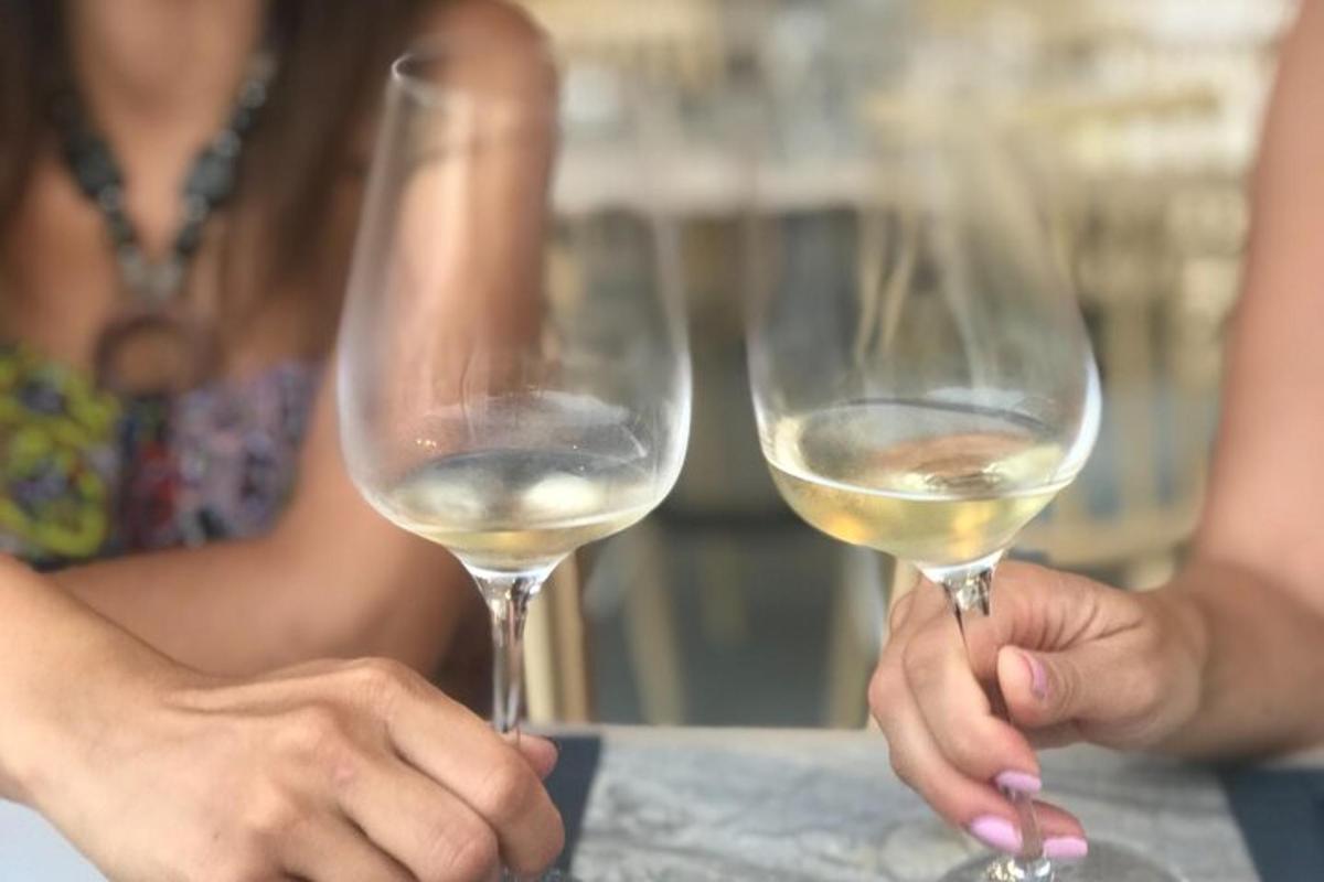 două persoane care țin în mână pahare de vin alb