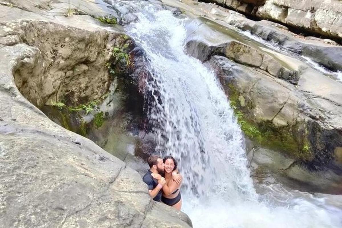 a man and woman standing in front of a waterfall