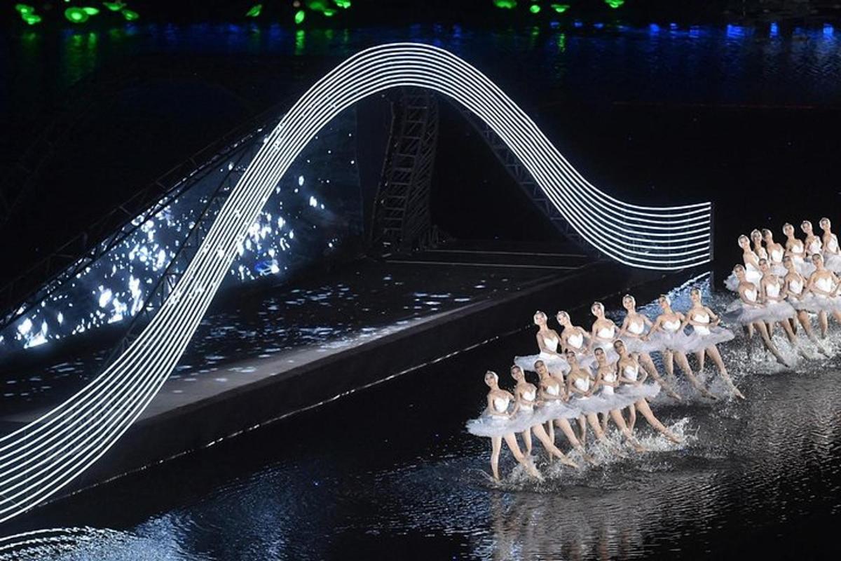a group of flamingos standing in the water under a bridge