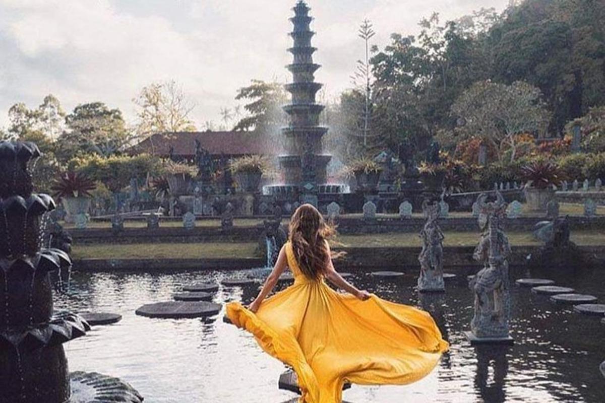 seorang wanita bergaun kuning berdiri di air mancur