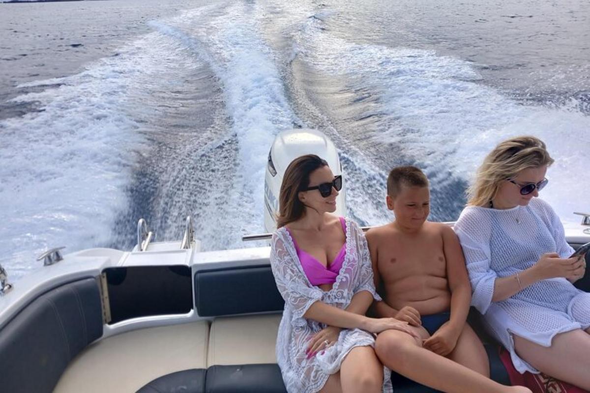 tři lidé sedící na zadní straně lodi
