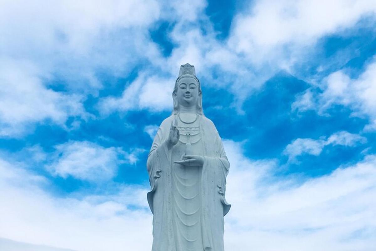 una statua di una donna in piedi davanti a un cielo nuvoloso