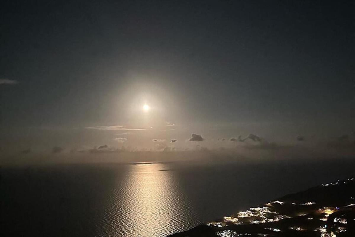 úplněk vycházející nad oceánem v noci