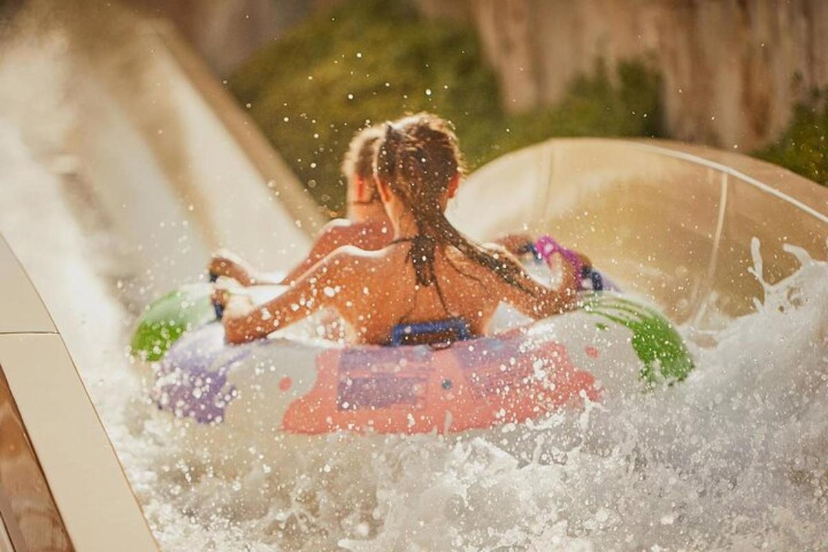 two girls riding a raft on a water slide