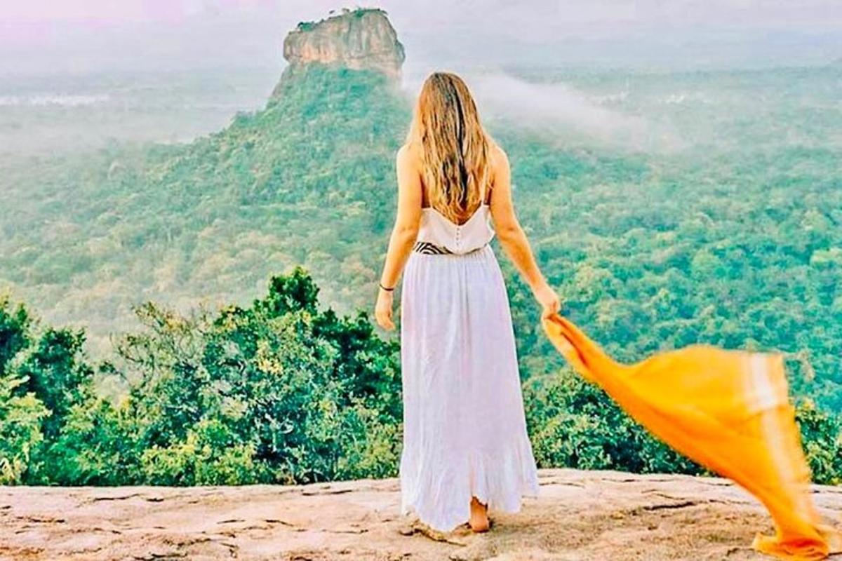 a woman in a white dress standing on top of a mountain