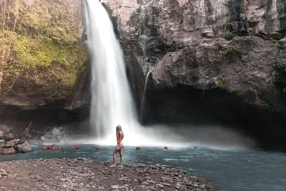 eine Frau steht vor einem Wasserfall