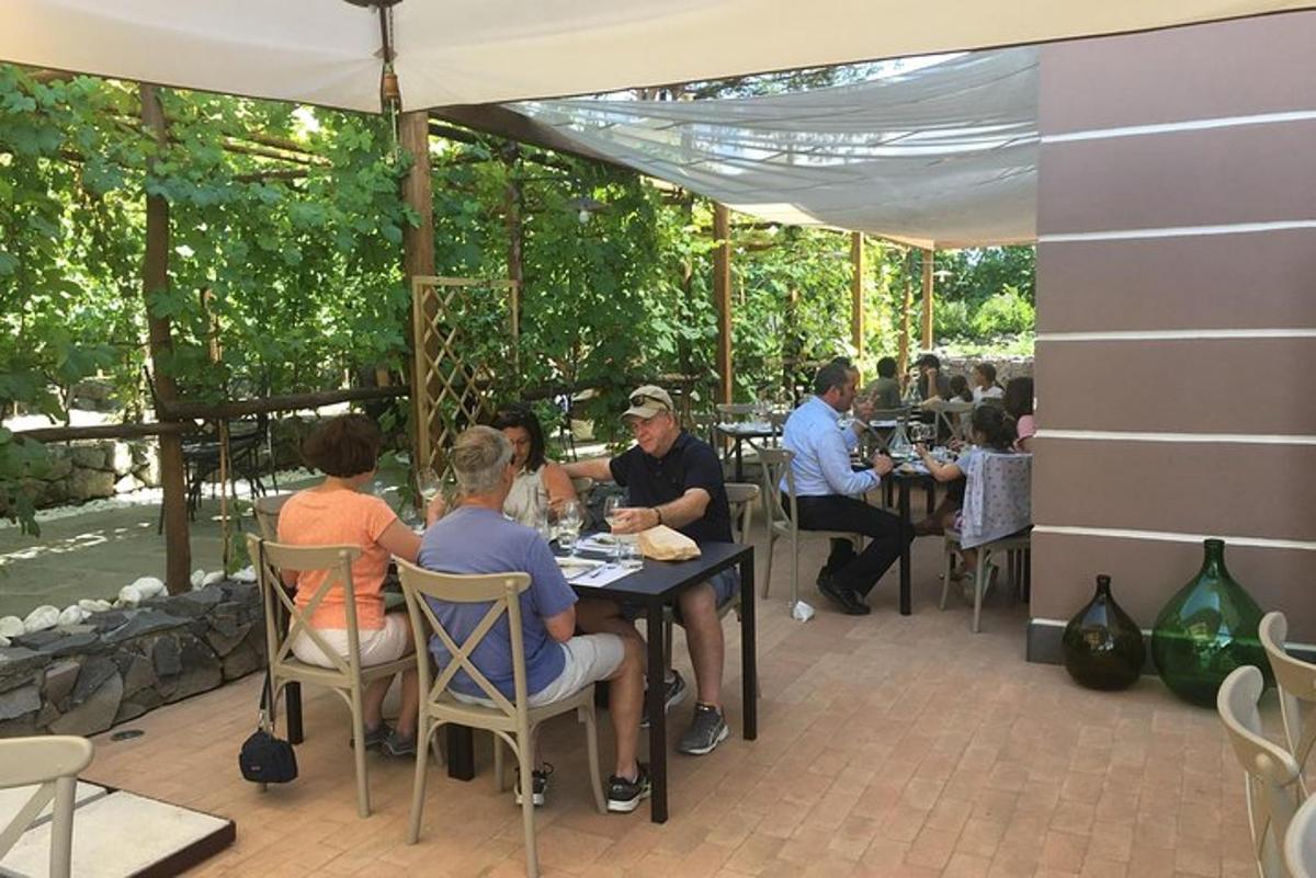 група людей, що сидять за столом під парасолькою