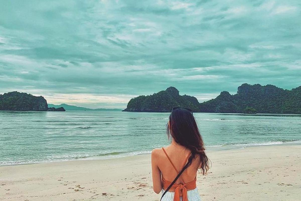 una donna in piedi sulla spiaggia che guarda l'acqua