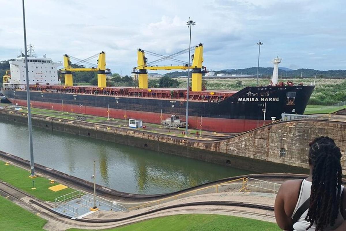 una donna seduta su un muro che guarda una grande nave