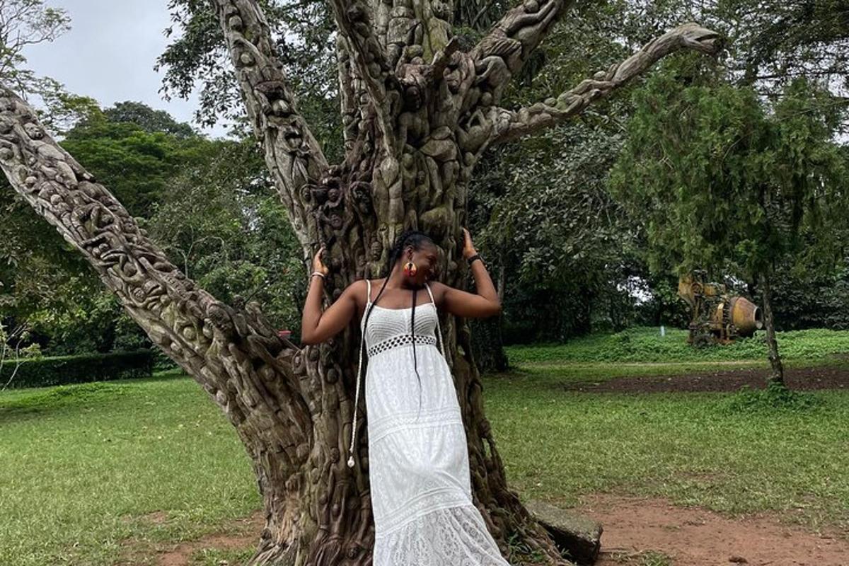 a woman in a white dress standing next to a tree