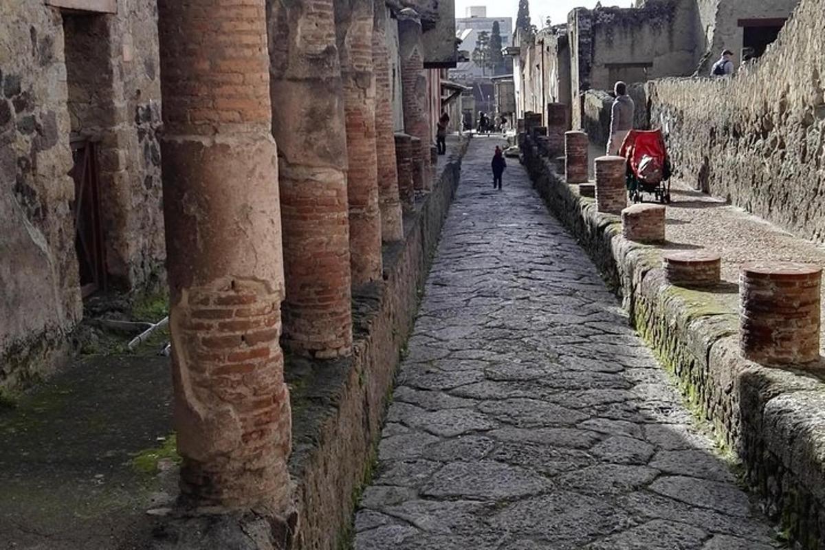 ulička se sloupy a osoba kráčející po ulici