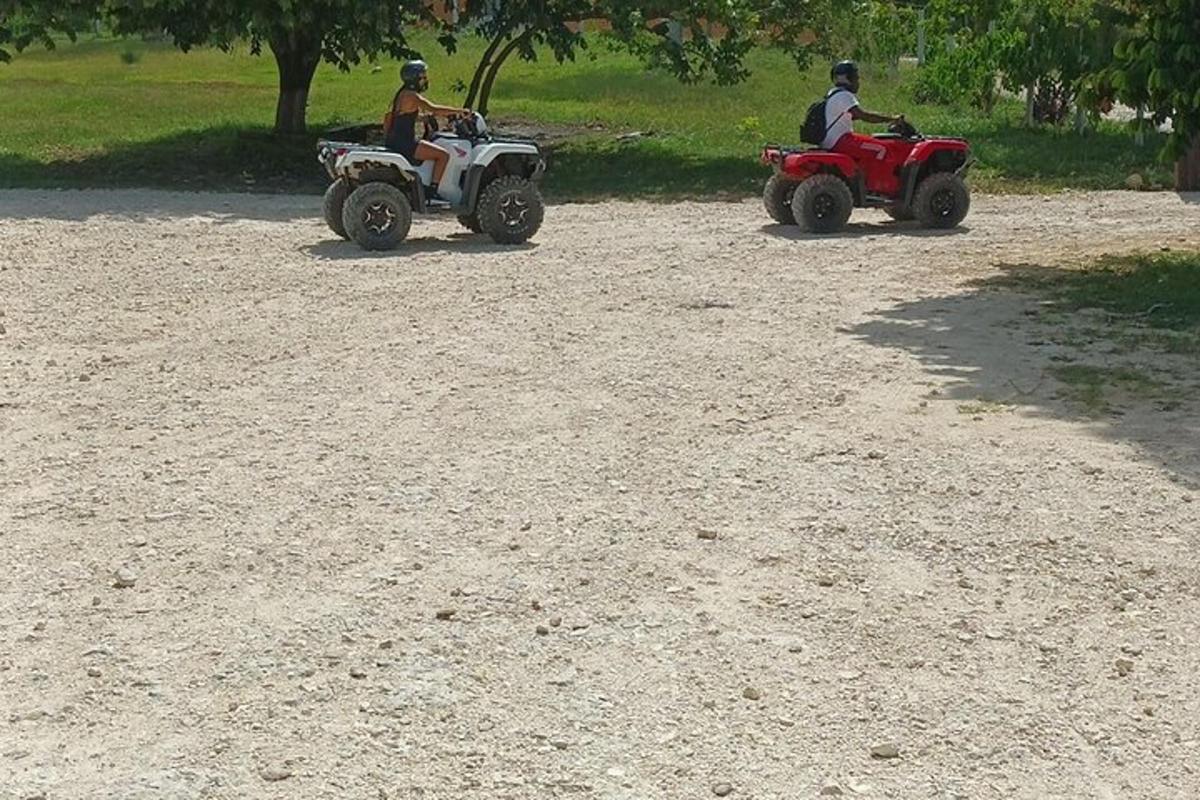 to personer kører på ATV'er på en grusvej