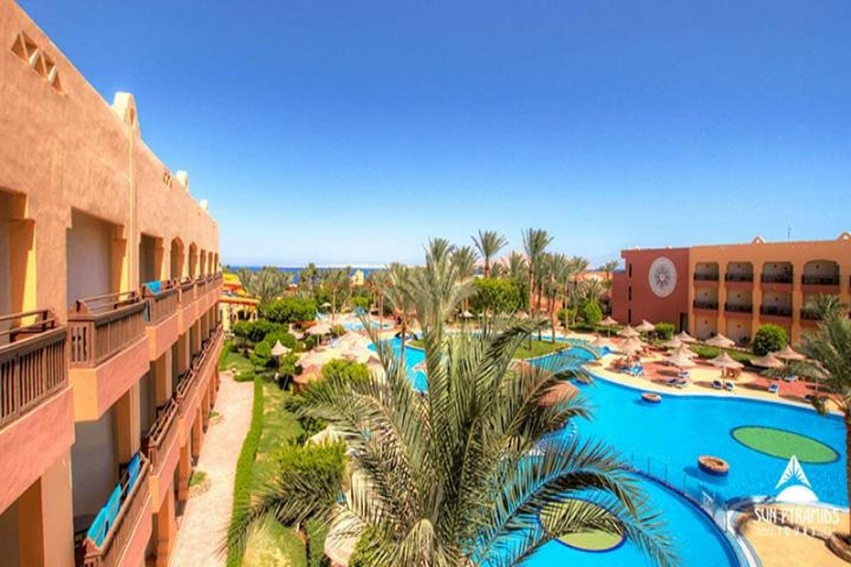 Un complejo con una gran piscina con palmeras.
