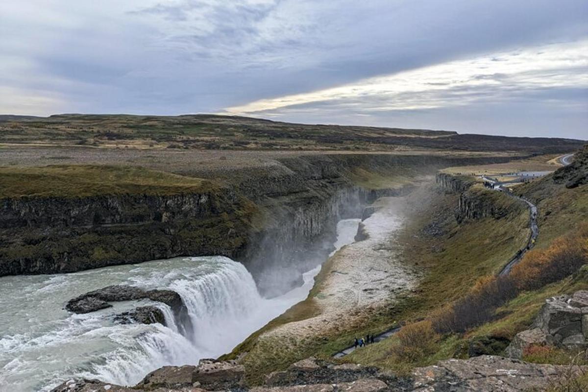et vandfald på siden af en klippe ved siden af en flod