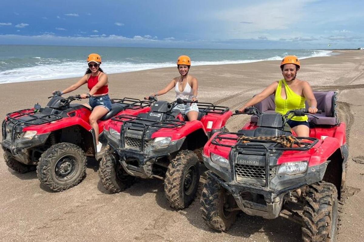 trei persoane stând pe ATV-uri pe plajă