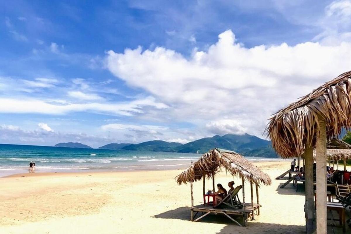 skupina ljudi, ki sedijo pod senčniki na plaži