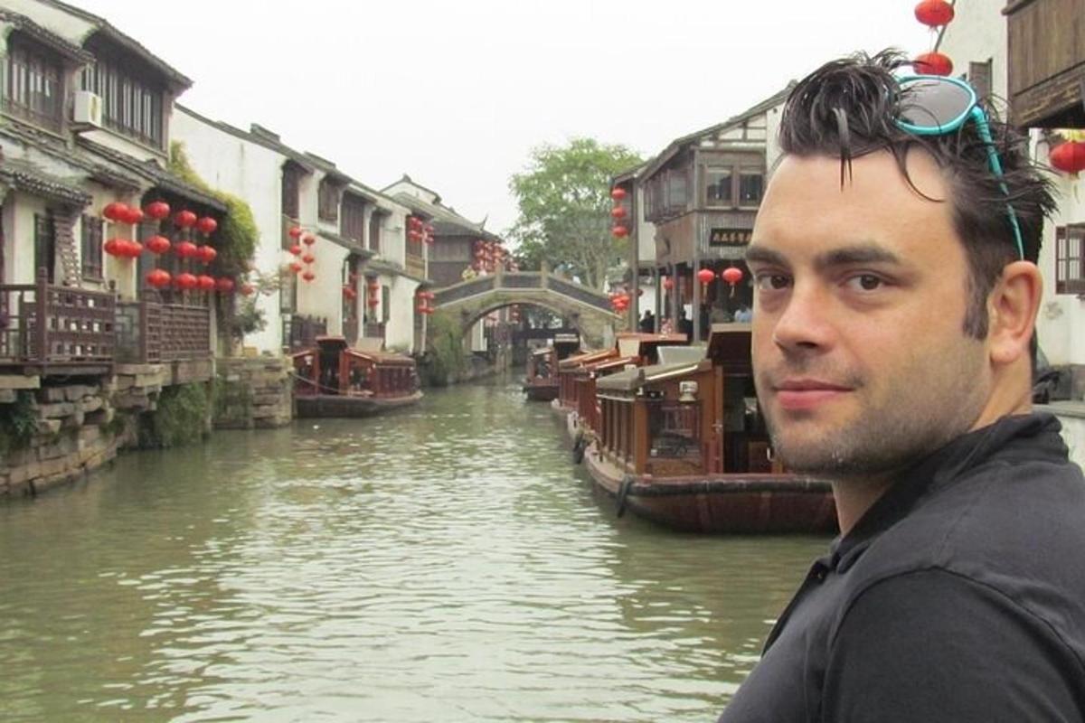 a man with sunglasses on his head standing next to a canal