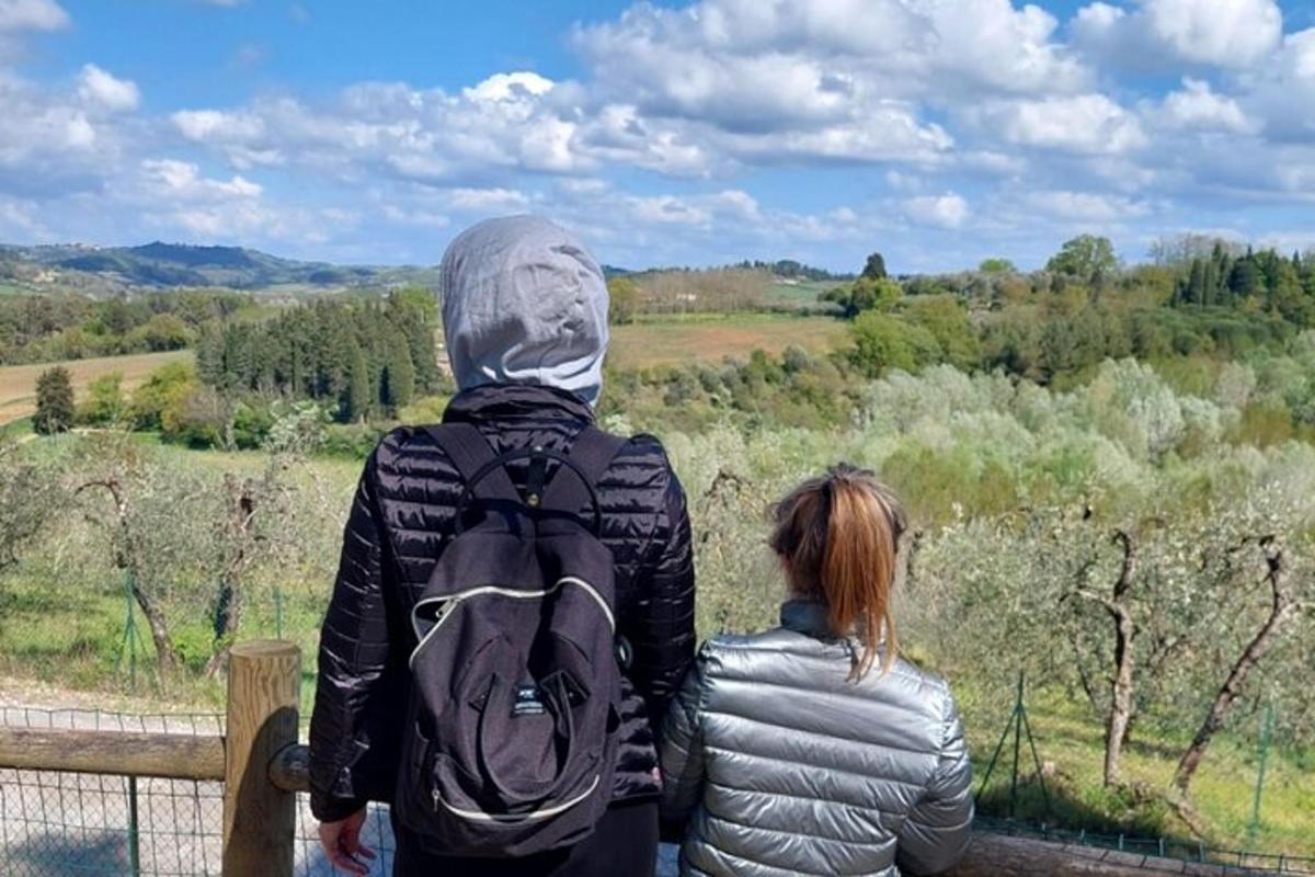 Un hombre y una mujer de pie sobre una valla mirando hacia un campo.