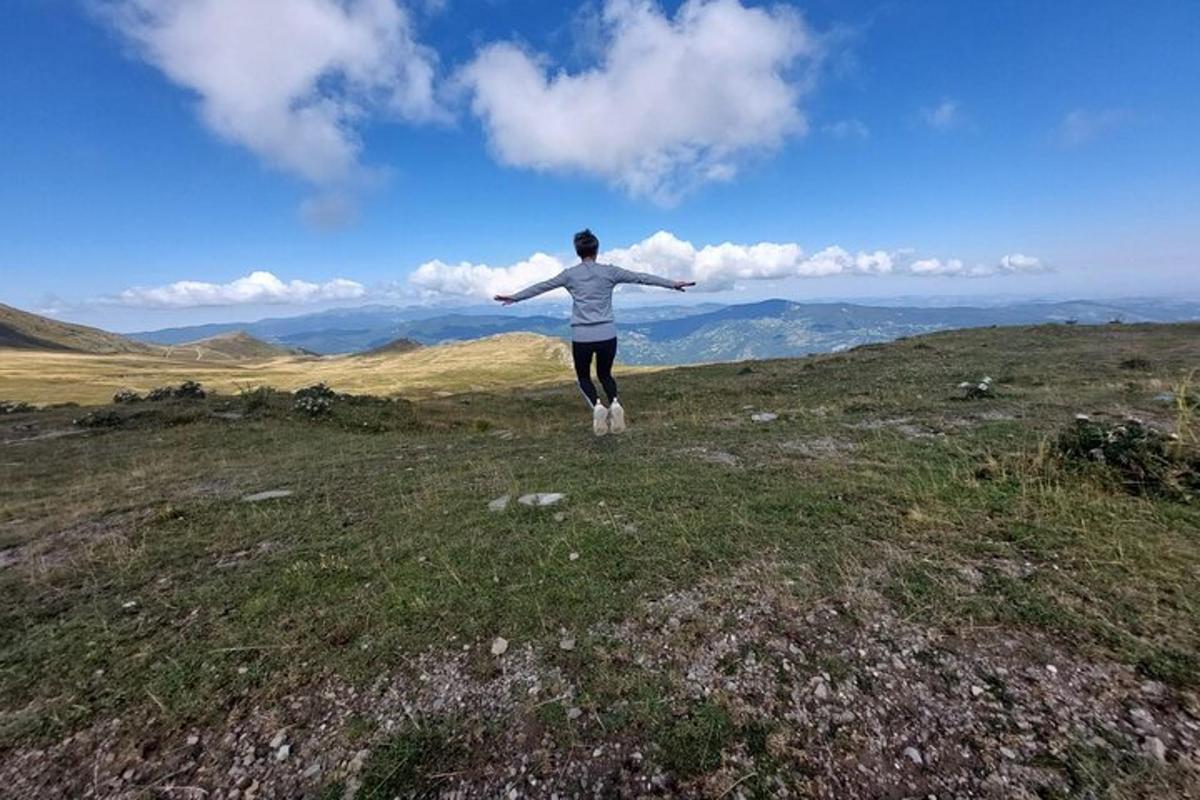 una persona parada en la cima de una colina con los brazos extendidos