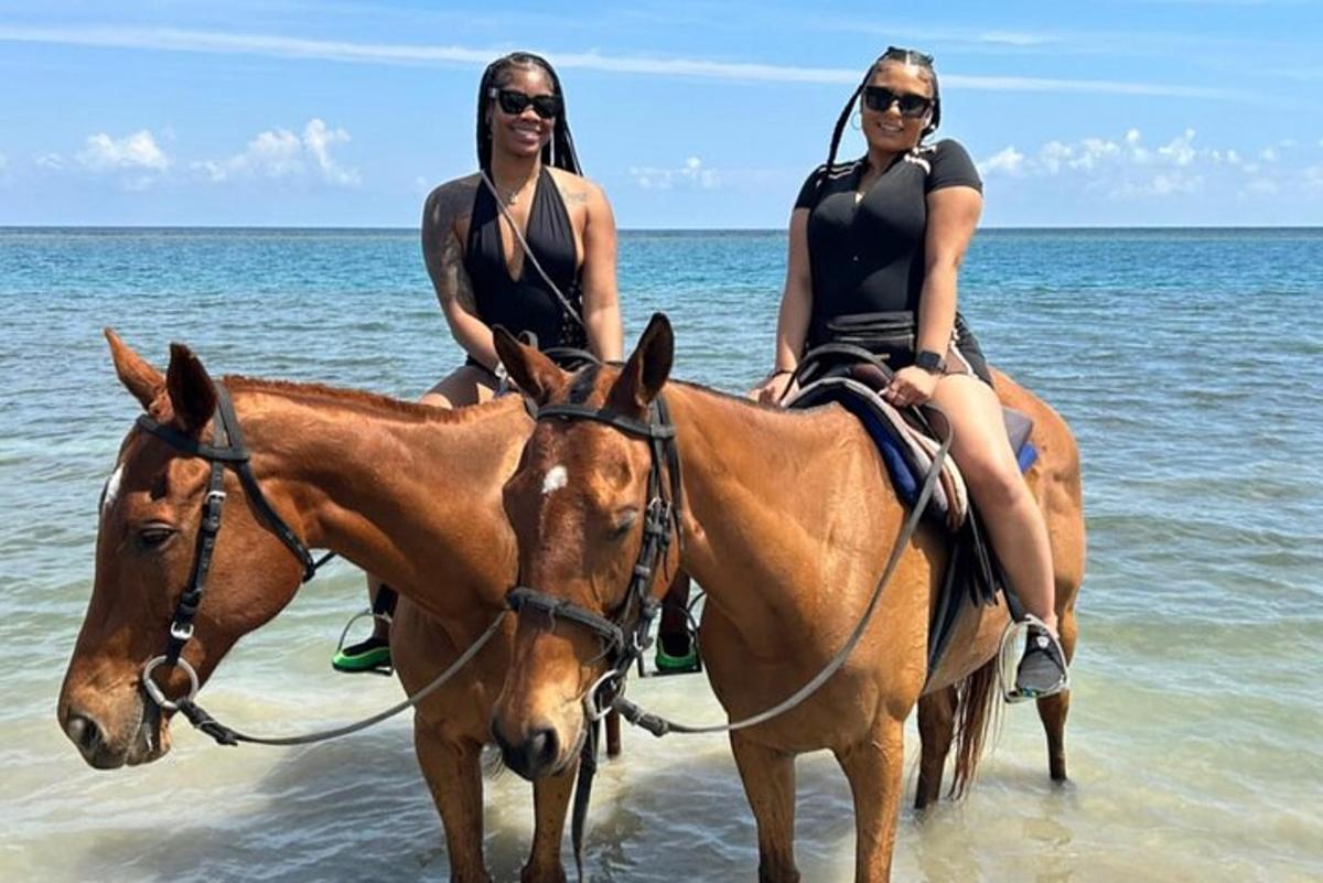 dua wanita menunggang kuda di dalam air di pantai