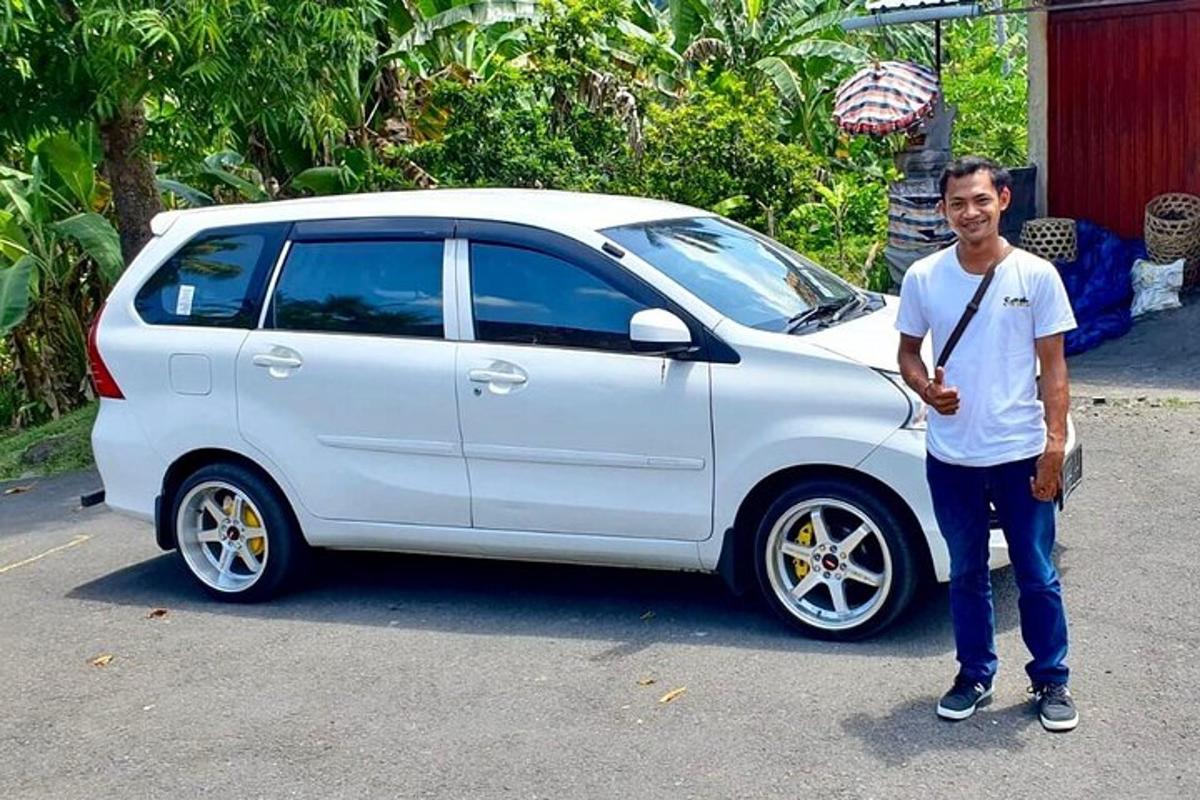 một người đàn ông đang đứng cạnh một chiếc xe màu trắng