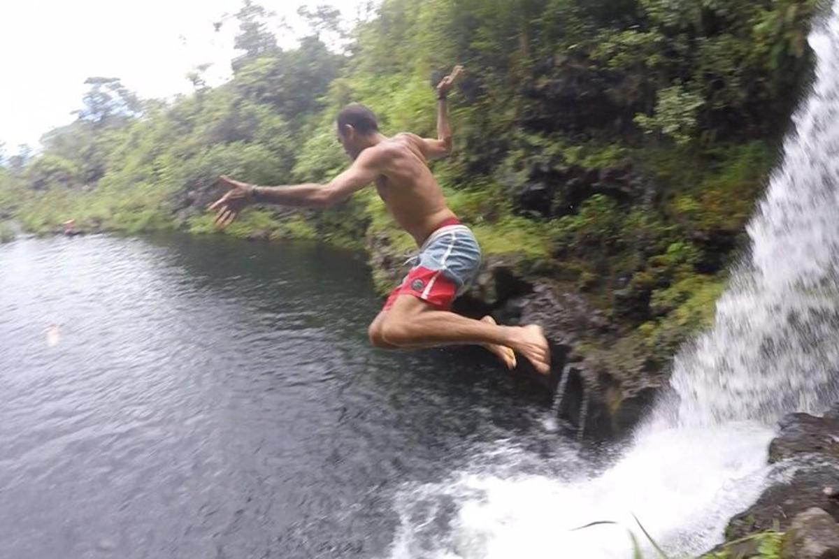 un uomo che salta da una cascata in uno specchio d'acqua