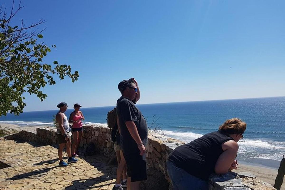 Μια ομάδα ανθρώπων που στέκονται σε έναν τοίχο κοντά στον ωκεανό