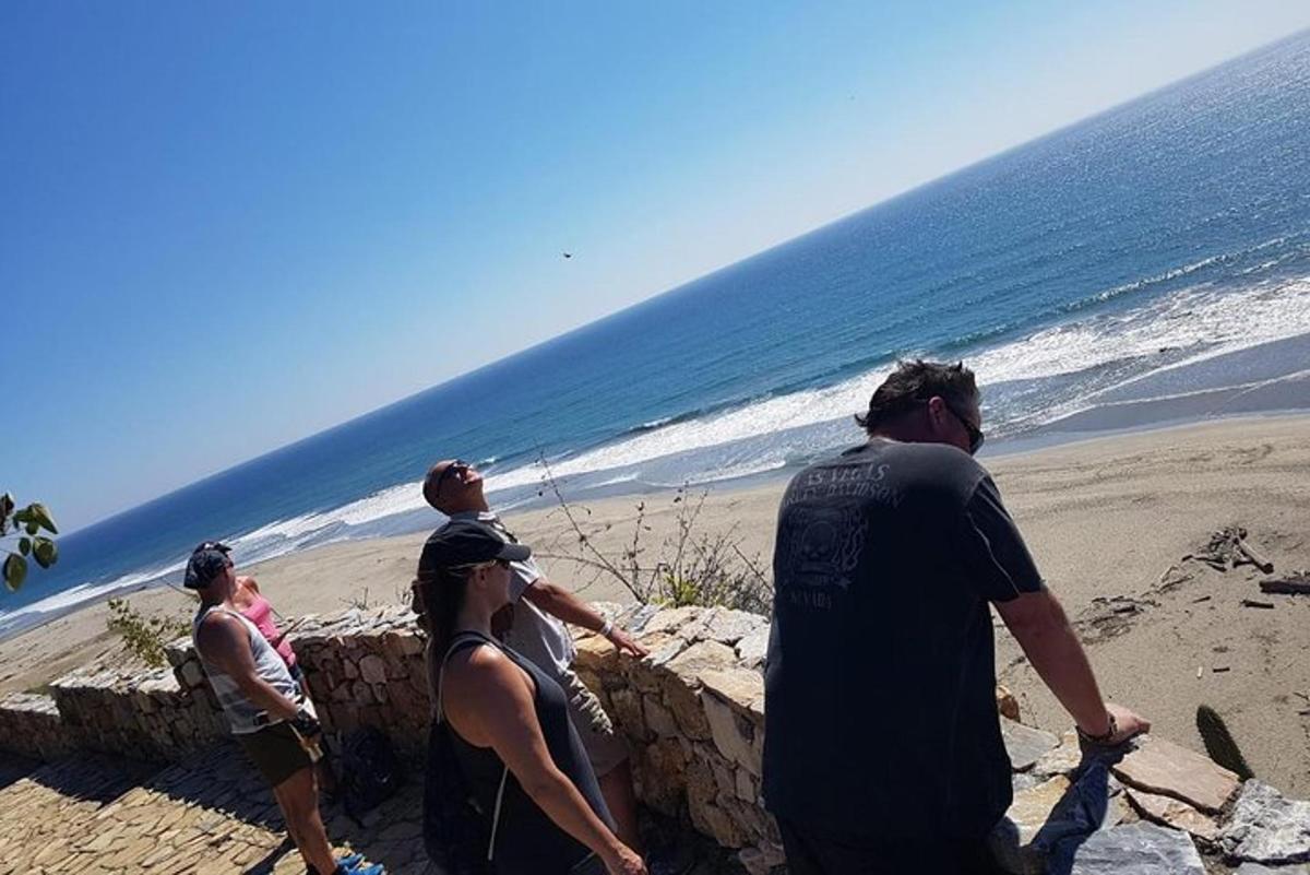 Μια ομάδα ανθρώπων που στέκονται σε έναν τοίχο κοντά στην παραλία