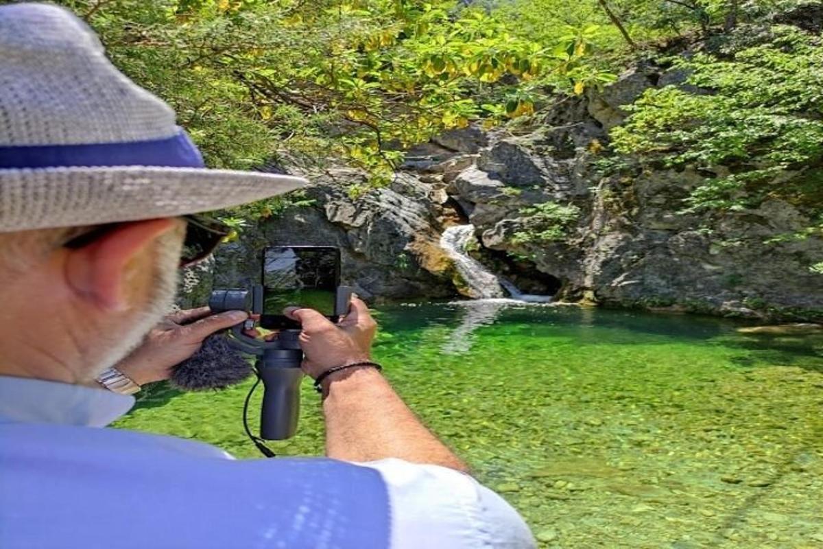 moški, ki s fotoaparatom fotografira reko