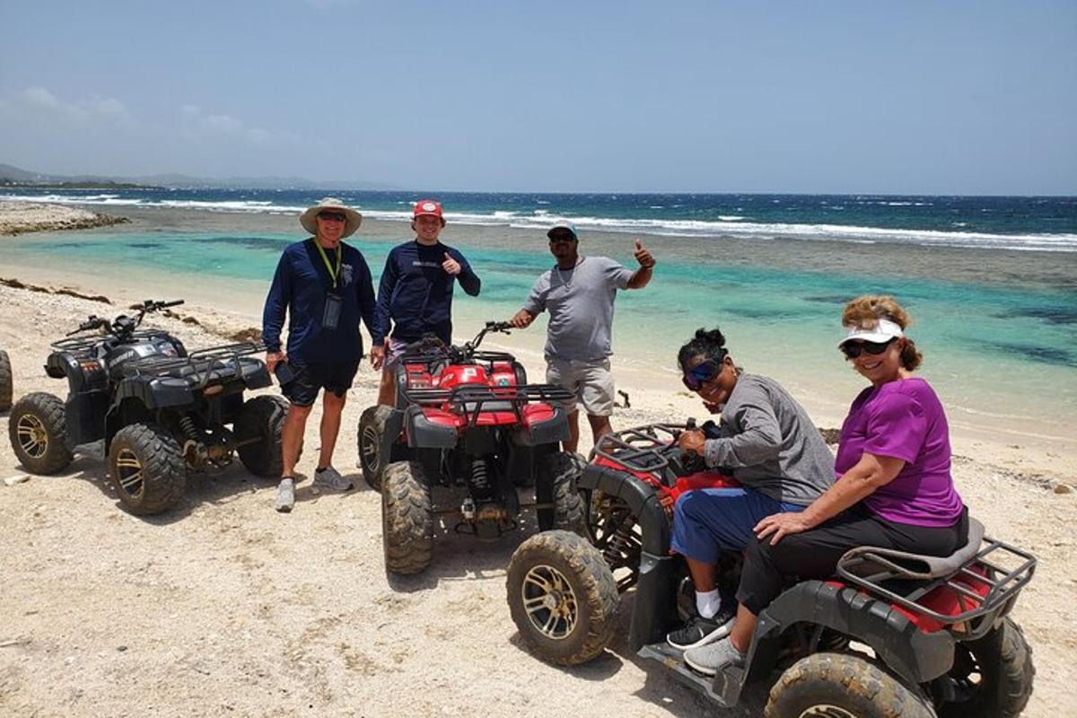 a group of people standing around atvs on the beach