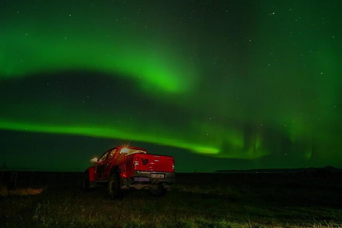 Rauður vörubíll á akri undir norðurljósum