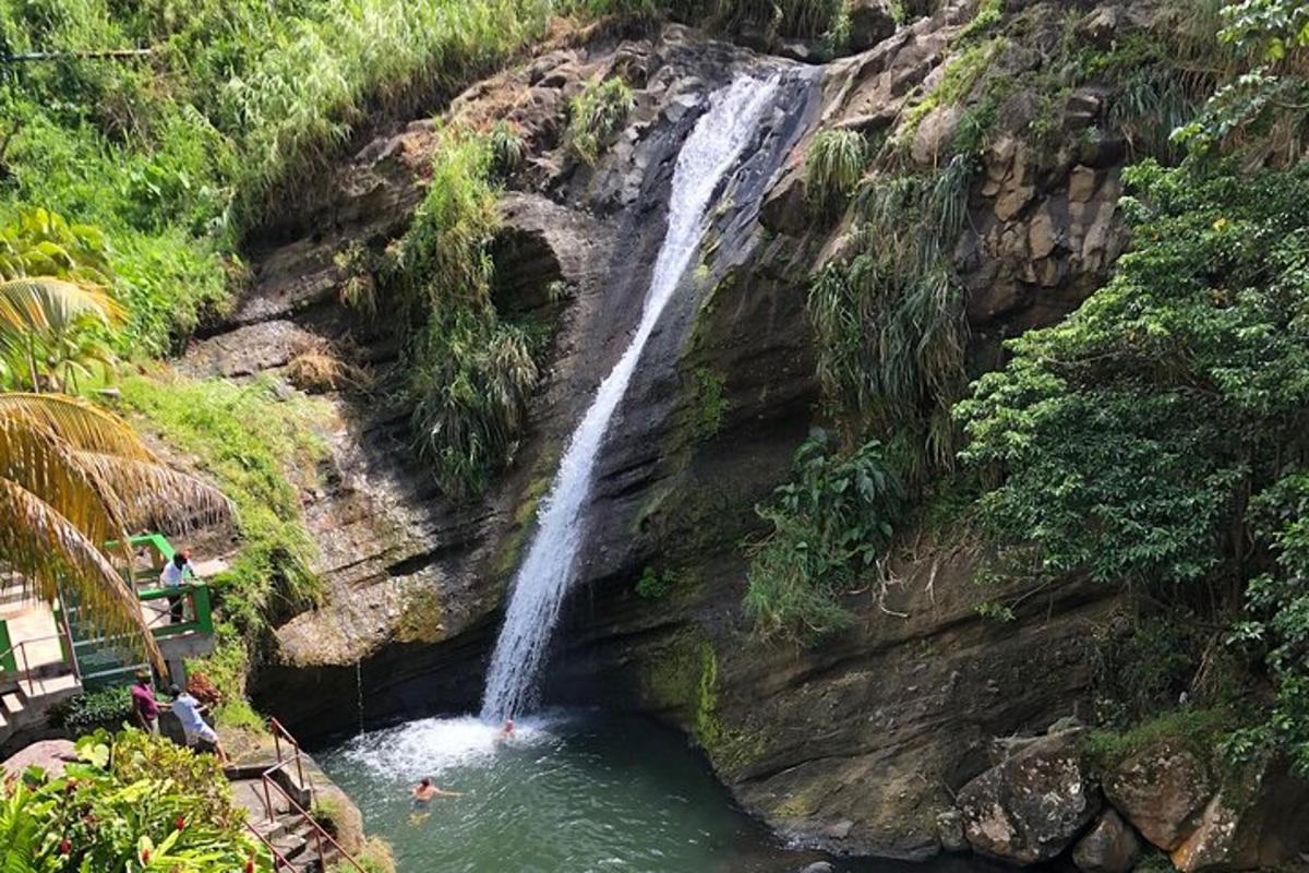 a waterfall on a cliff with people swimming in the water