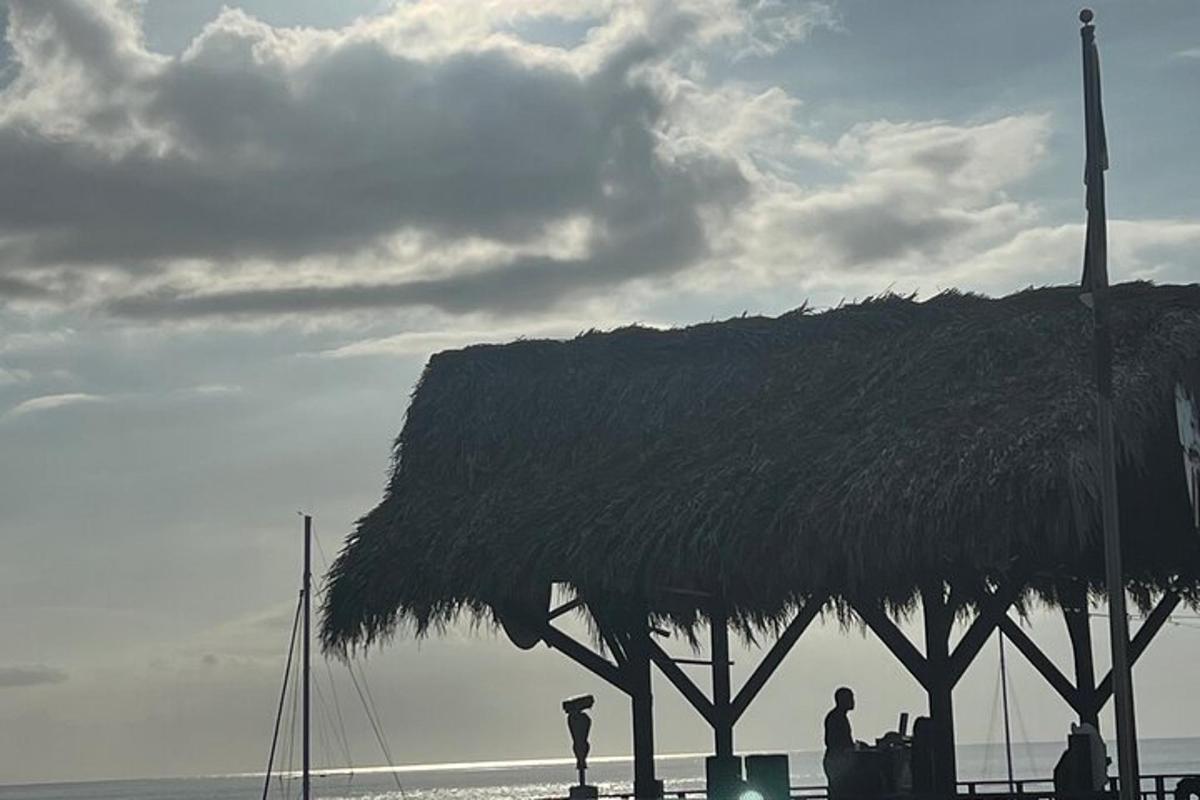 pondok jerami dengan orang berdiri di bawahnya di pantai