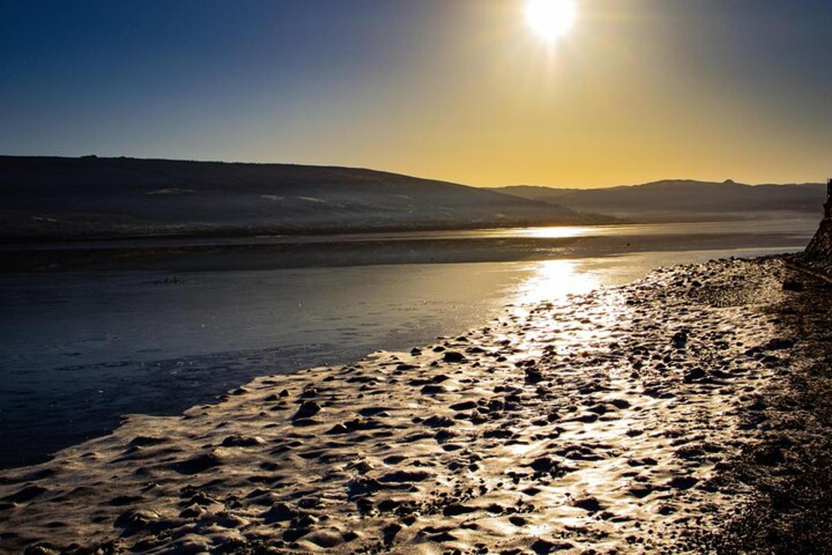 una spiaggia con il sole che sorge sull'acqua