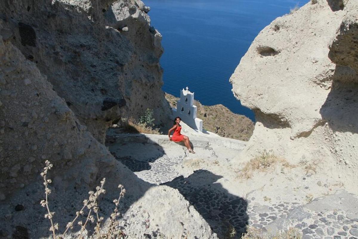 una dona baixant per un turó rocós amb una església