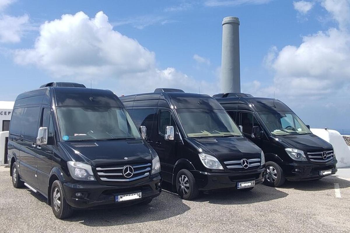 trys juodi furgonai pastatyti automobilių stovėjimo aikštelėje su švyturiu fone