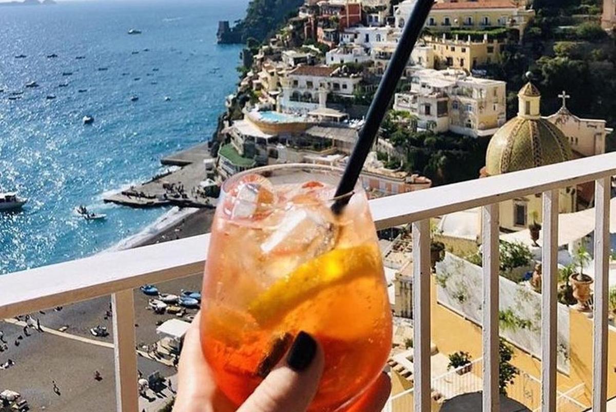 osoba držící drink s výhledem na oceán