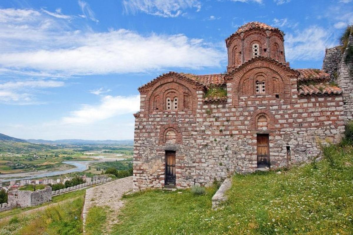 un vecchio edificio in mattoni su una collina con un fiume