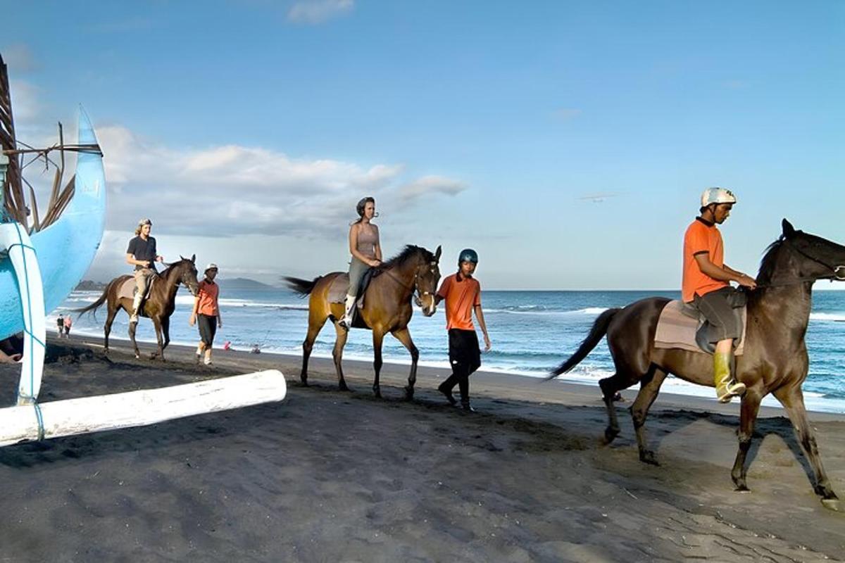 un grup de persones muntant a cavall a la platja