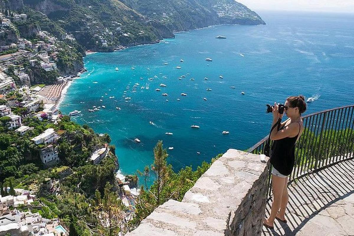 o femeie care fotografiază oceanul cu un aparat foto