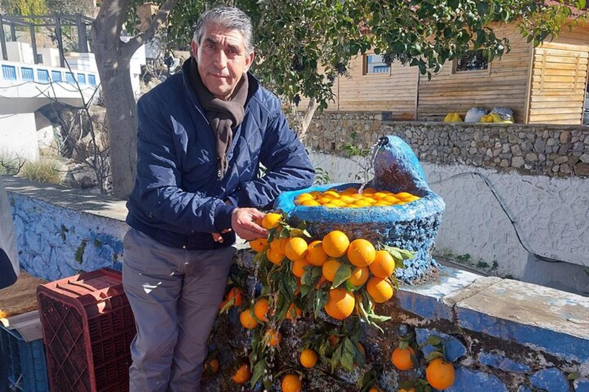 moški, ki stoji poleg kupa pomaranč