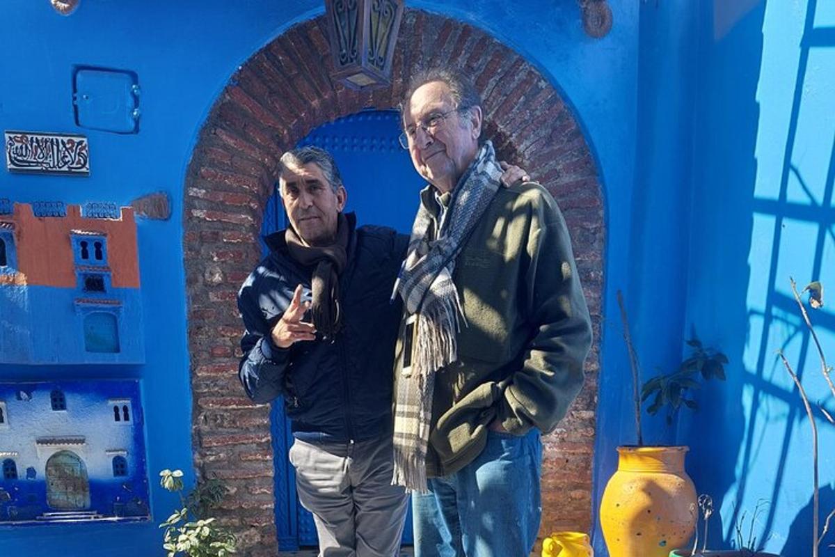 doi bărbați stând în fața unui perete albastru