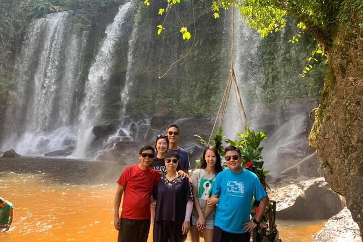 um grupo de pessoas em pé em frente a uma cachoeira